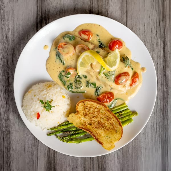 Chicken in creamy sauce with spinach, tomatoes, lemon, rice, asparagus, and garlic bread.