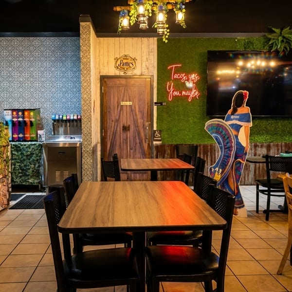 Interior of a vibrant Mexican restaurant with brick, stone, and grass walls, and wooden tables.